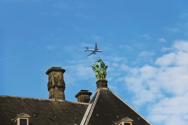 Flying plane over roof of the Royal Palace in Amsterdam — Stock Photo, Image