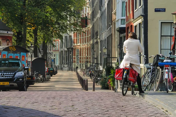 Kvinna som rider en cykel i Amsterdam, Nederländerna — Stockfoto