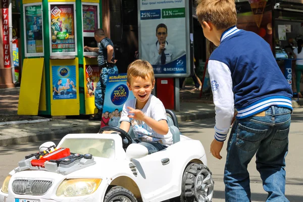 Niños en la zona de juegos montando un coche de juguete. Nikolaev, Ucrania — Foto de Stock