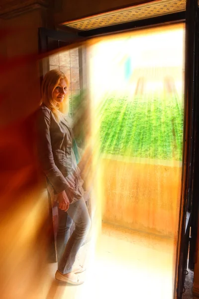 Menina na varanda da casa em raios dourados de sol — Fotografia de Stock
