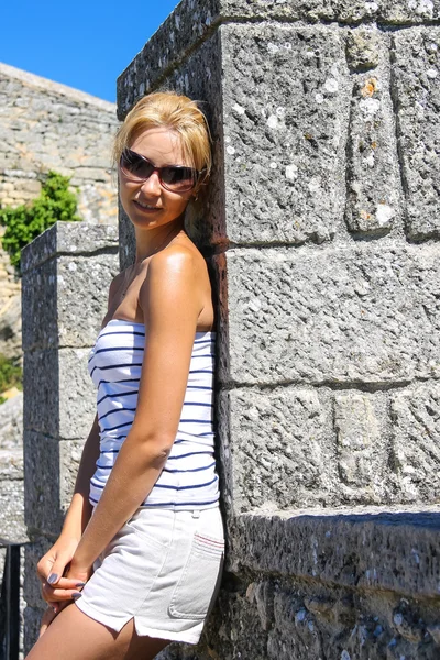 Attractive girl in sunglasses near the fortress wall — Stock Photo, Image