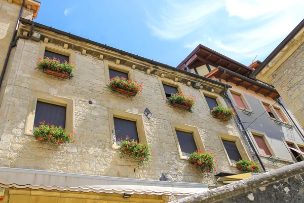 Malebný dům s květinami na windows v italském městě — Stock fotografie