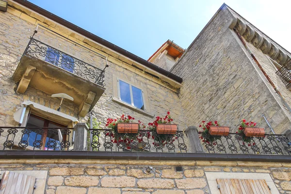Pintoresca casa con flores en el balcón de la ciudad italiana —  Fotos de Stock