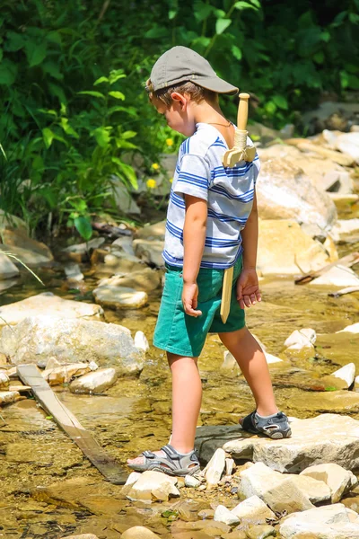 The kid plays near a mountain stream — Stock Photo, Image
