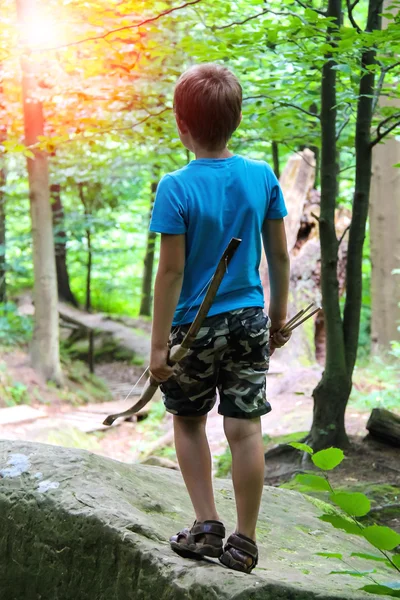 Pojke med pil och båge på en promenad i parken. — Stockfoto