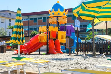 Çocuk oyun alanı, sandalye ve şemsiye plajda  