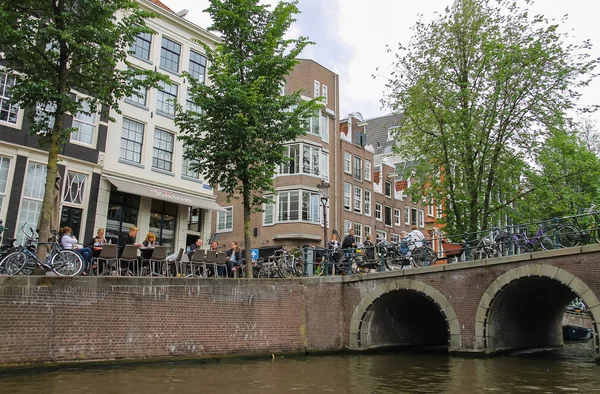 Lidé v okolí kavárna na nábřeží kanálu v Amsterdamu — Stock fotografie