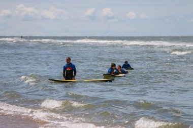 Onların s ile deniz dışında yürüyüş wetsuits genç sörfçü arkadaşlar