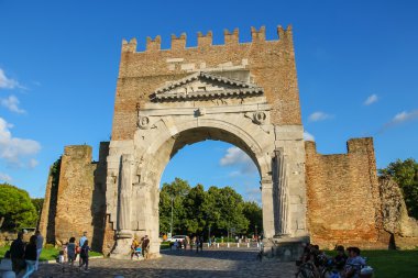 Tourists walking near the ancient arch of Augustus (Arco di Augu