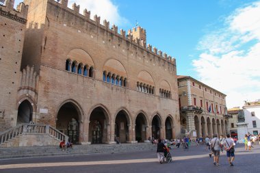Tourists walking near the ancient buildings and statue of Pope P