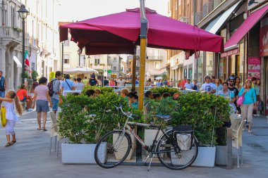 Walking people and outdoor cafe with bicycle near it on the main