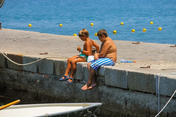 Twee kleine jongens die zitten op de pier in de buurt van de afgemeerd boot. Elba ik — Stockfoto