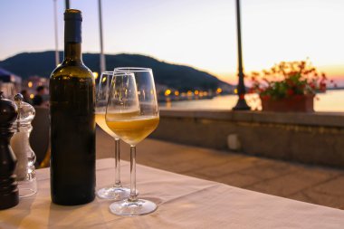 Bir şişe beyaz şarap ve üzerinde Restoran masada iki bardak 