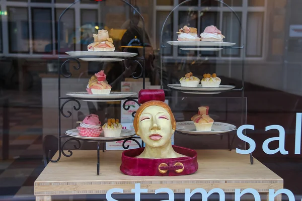Platen met kleine cakes in het venster van de zoetwaren-winkel — Stockfoto