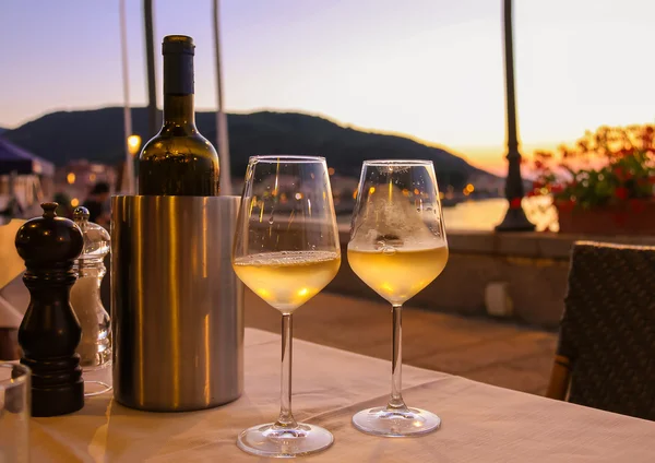 Garrafa de vinho branco e dois copos na mesa do restaurante em Imagens De Bancos De Imagens Sem Royalties