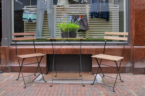 Tisch und zwei Stühle auf dem Bürgersteig vor der Kleiderkammer — Stockfoto