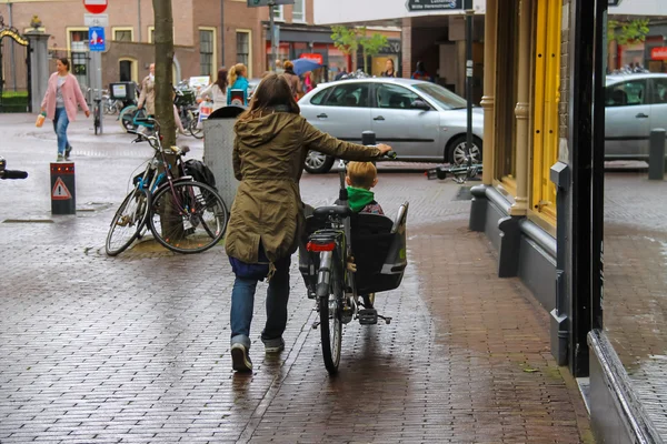 A woman carries a child by bicycle in the  historic center of Ha — Stock Photo, Image