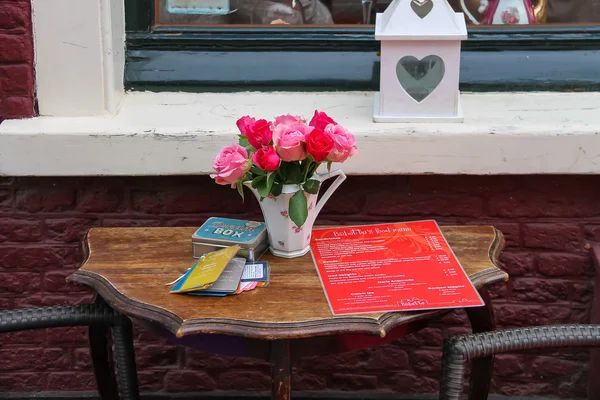 Table d'extérieur avec roses dans un vase et menu des salons de thé Bij Babet — Photo