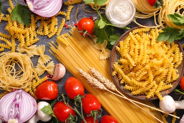 Assorted raw pasta and ingredients — Stock Photo, Image