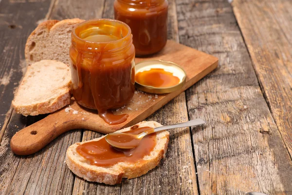 Caramel in jars with bread — Stock Photo, Image