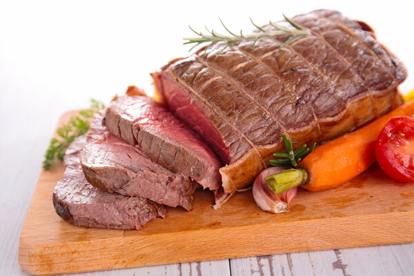 Roast beef and carrot on board on table