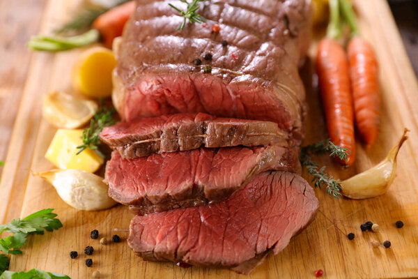 Roast beef and slices on wooden board