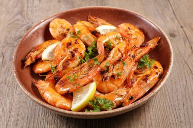 Ahşap zemin üzerinde ızgara karides ve baharatlar.