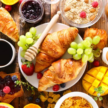 Kahvaltı. Kahve fincanı, kruvasan, mısır gevreği ve meyve.