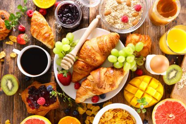 Kruvasan, kahve fincanı, mısır gevreği ve meyve.