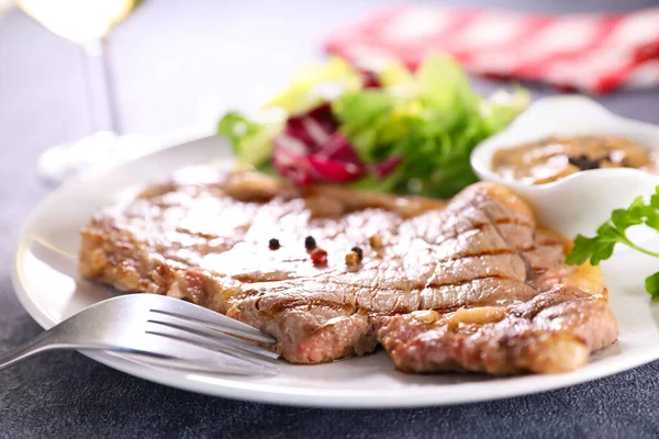 Kızarmış biftek, sos ve marul.