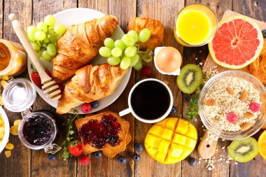 Kahve fincanı, kruvasan ve taze meyveli kahvaltı.