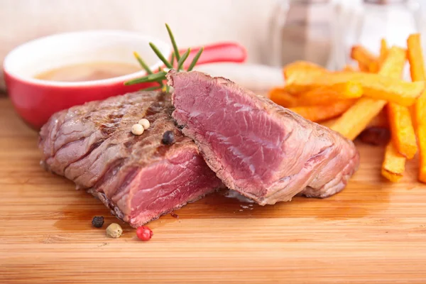 Hovězí maso a hranolky na dřevěné desce — Stock fotografie