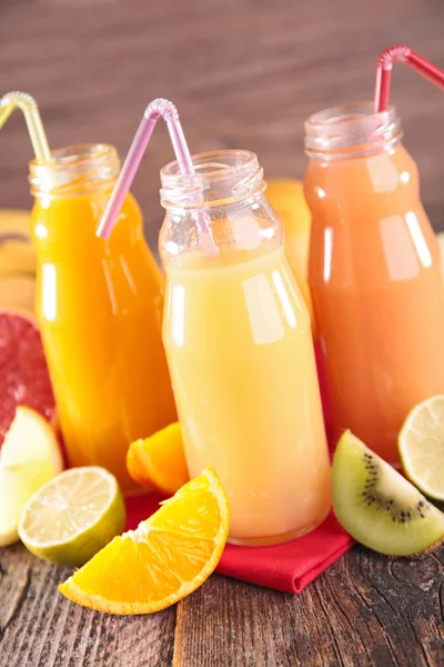 Fruit juice in glass bottles with straw — Stock Photo, Image