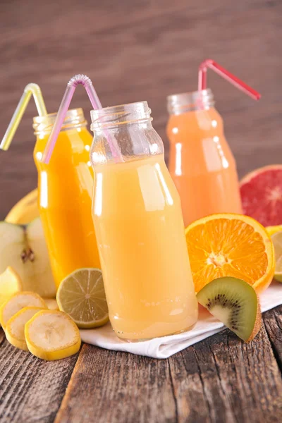 Fruit juice in glass bottles with straw — Stock Photo, Image