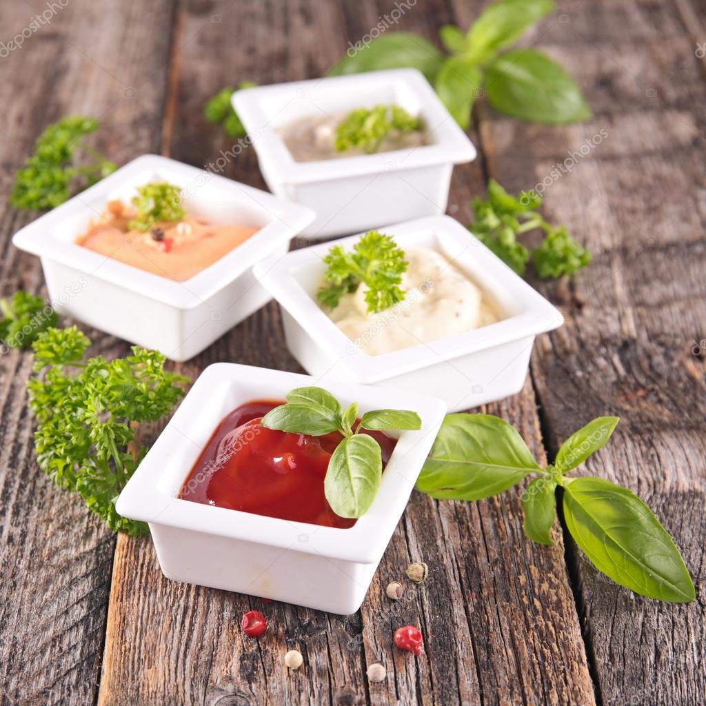 Assortment of sauces with basil on wood