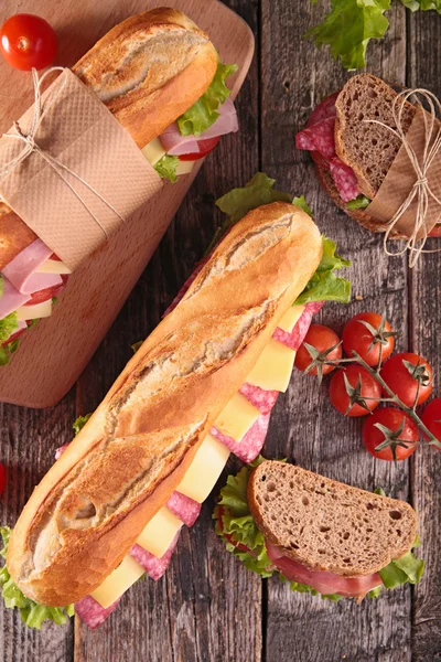 Tasty sandwiches with bacon, salami and vegetables — Stock Photo, Image
