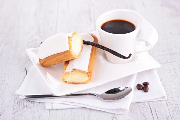 Eclair with coffee on table — Stock Photo, Image