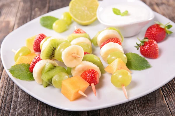 Різні види фруктів на палички з dip йогурт на білий пластини служив на дерев'яні таблиці — 图库照片