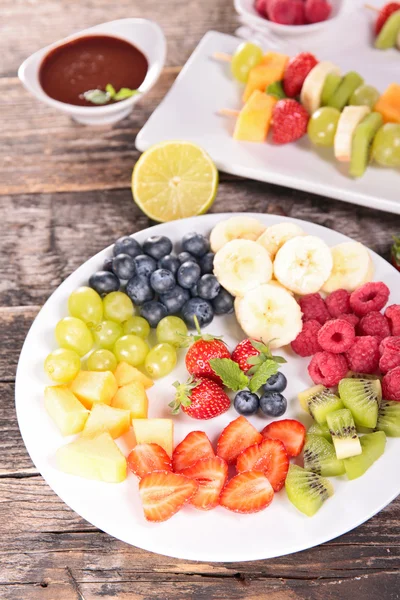 Gesneden fruit op platen en duik van chocolade — Stockfoto