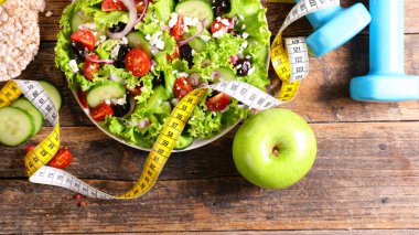 Diyet gıda konsepti, yeşil elmalı sağlıklı sebze salatası ve aktif yaşam tarzı için mavi dambıl.