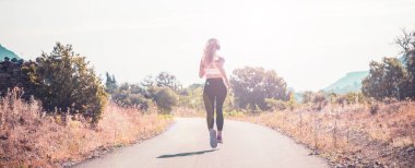 Spor giyim sektöründe aktif bir kadın gün doğumunda doğada koşuyor.