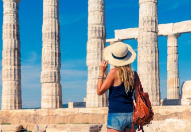 Kısa boylu, şapkalı ve çantalı kadın Yunanistan 'daki antik tapınağın tadını çıkarıyor, seyahat yeri, turizm