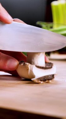 Ahşap tahtada taze mantar kesen şefin eli. Sosyal medya için dikey video