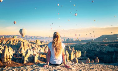 Gezgin kadın, Cappadocia 'daki sıcak hava balonlarının, seyahatlerin, turizmin muhteşem manzarasının tadını çıkarıyor.