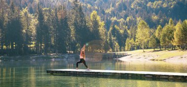 Yoga yapan kadın, sakin bir dağ manzarasında poz veriyor.