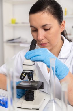 Bir laboratuarda mikroskop ile çalışan kadın. Tonlama resim