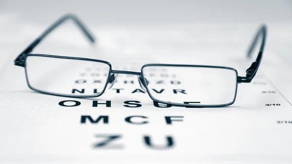 Gafas modernas Clear Black en una carta de pruebas a la vista . — Foto de Stock