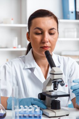 bir laboratuarda mikroskop ile çalışan kadın.