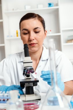 bir laboratuarda mikroskop ile çalışan kadın.