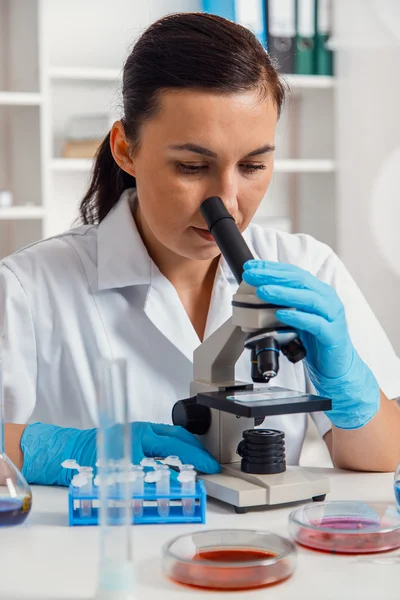 工作用显微镜在实验室中的女子. — 图库照片